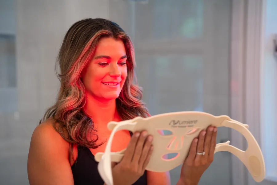 A woman holding her illuminated Time Keeper mask at home